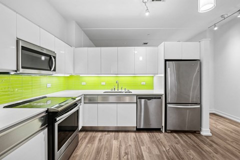 A modern kitchen with stainless steel appliances and wooden floors.