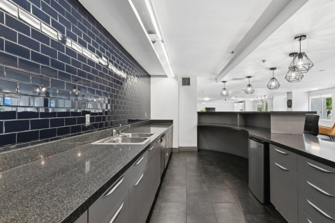 A modern kitchen with dark grey cabinets and a black tile backsplash.