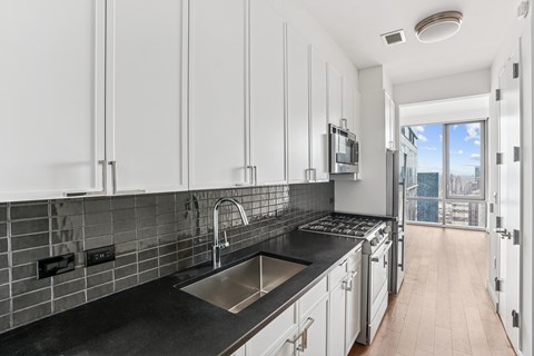 A kitchen with white cabinets and a black countertop.