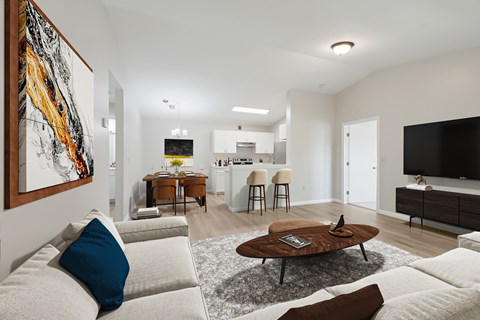 A living room with a white couch and a painting on the wall.