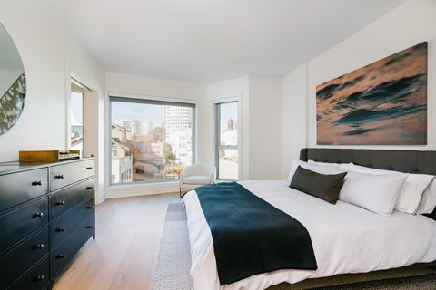 A bedroom with a large bed and a painting on the wall.