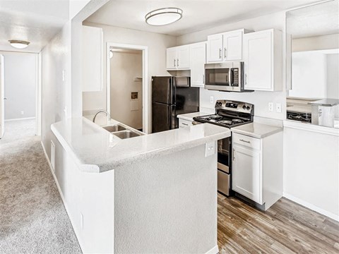 A kitchen with white cabinets and a black refrigerator.