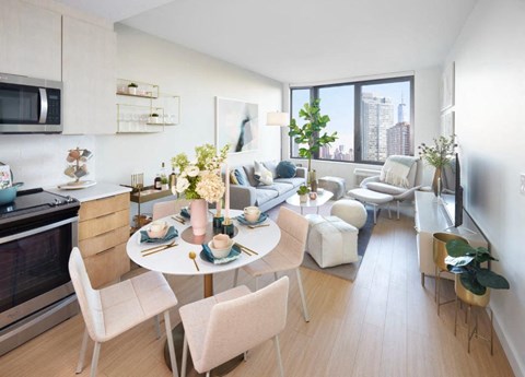 A modern kitchen and living room with a dining table set for two.