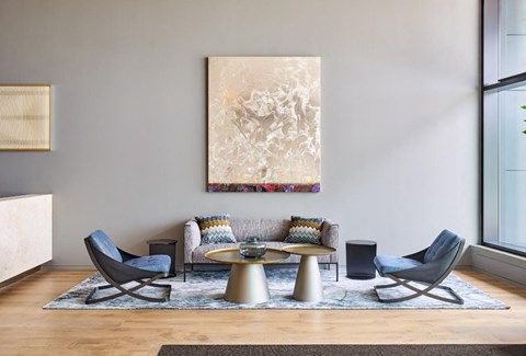 A living room with a large abstract painting on the wall and a coffee table in the center.