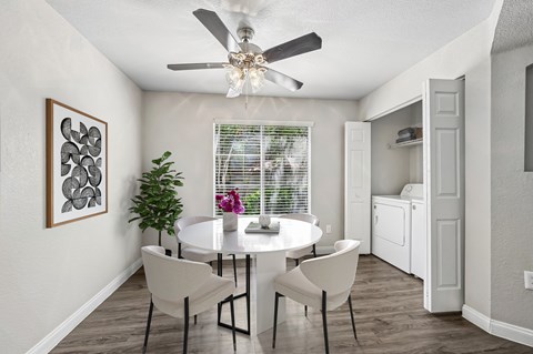 A dining room with a white table and chairs.