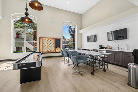 A room with a pool table and a kitchen area.