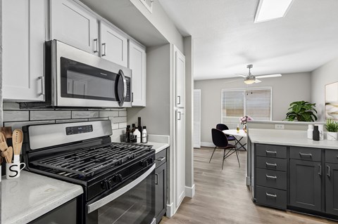 A modern kitchen with a black stove top oven and white cabinets.