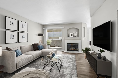 A modern living room with a grey sofa, a fireplace, and a large TV on the wall.