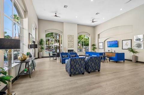 A spacious living room with a blue sofa set and a television mounted on the wall.