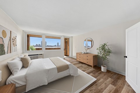 A bedroom with a large bed and a window overlooking a cityscape.
