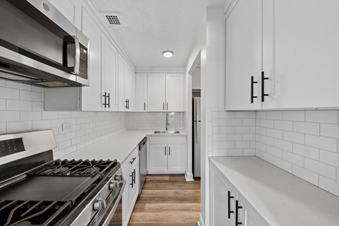 A modern kitchen with white cabinets and a black stove top.
