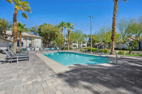 A swimming pool surrounded by palm trees and lounge chairs.