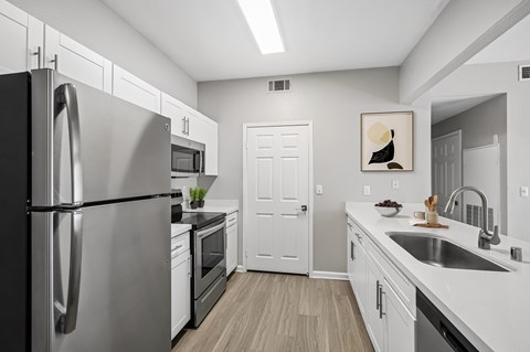 A modern kitchen with a stainless steel refrigerator and white cabinets.