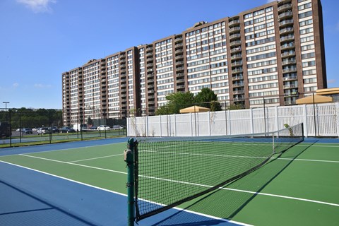 two tennis courts with buildings in the background