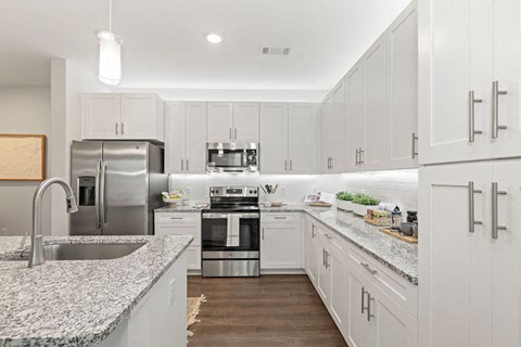 A modern kitchen with white cabinets and stainless steel appliances.