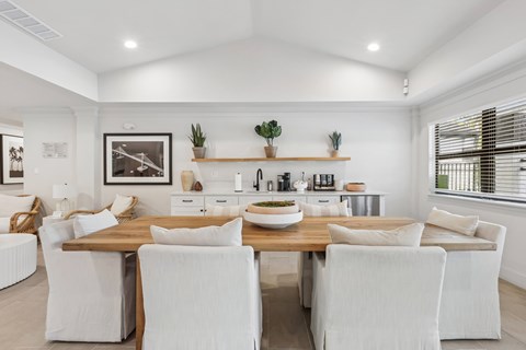 A dining room with a wooden table and white chairs.