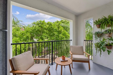 A balcony with a chair, couch, and potted plants.
