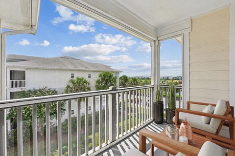 A balcony with a table and chairs overlooking a house.