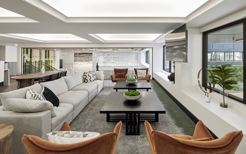 A modern living room with a long white sofa and a coffee table in the center.