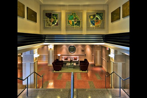 A hallway with a staircase and a red carpet.