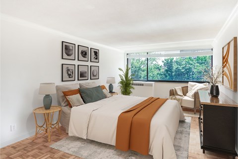 A bedroom with a large bed and a window overlooking trees.