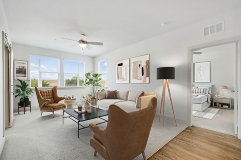 A living room with a brown chair in the foreground and a white couch in the background.