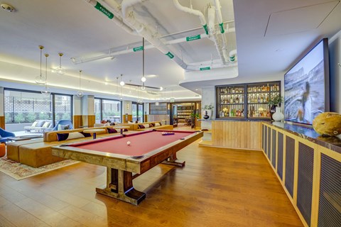 A pool table is in the middle of a room with a wooden floor.