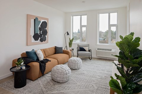 A living room with a brown couch, a black table, and a painting on the wall.