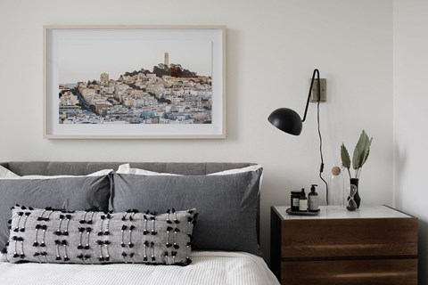 a bedroom with a bed with a pillow and a picture on the wall
