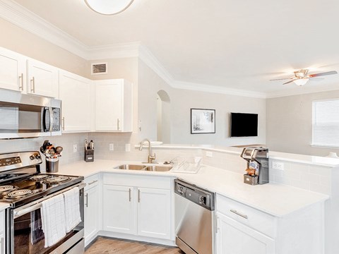 A kitchen with white cabinets and a stove top oven.