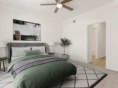A bedroom with a large bed and a ceiling fan.