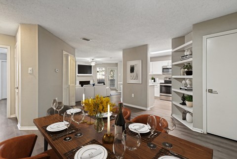 A dining room with a table set for two with a view of the kitchen.