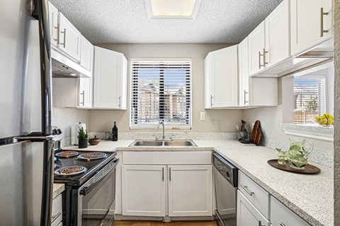 A kitchen with white cabinets and a black stove top.