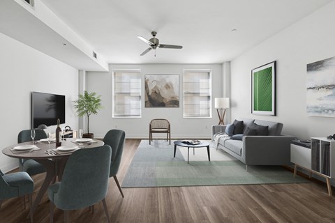 A modern living room with a dining table set for two and a grey couch.
