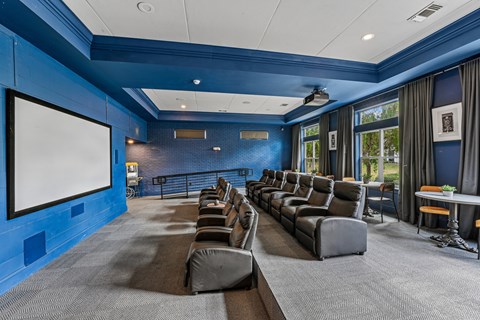 A movie theater with a row of seats and a large screen.