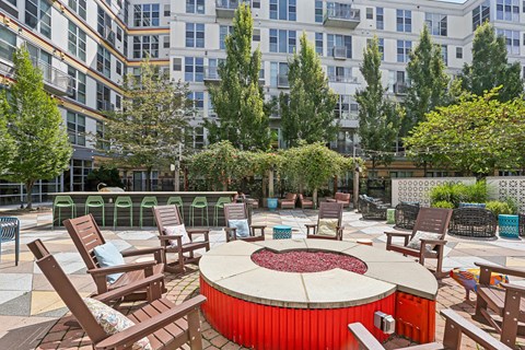 A red hot tub sits in the middle of a patio surrounded by chairs.