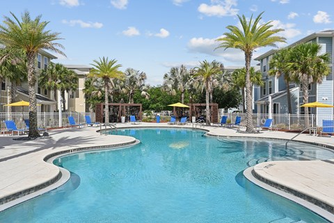 A large swimming pool surrounded by palm trees and lounge chairs.