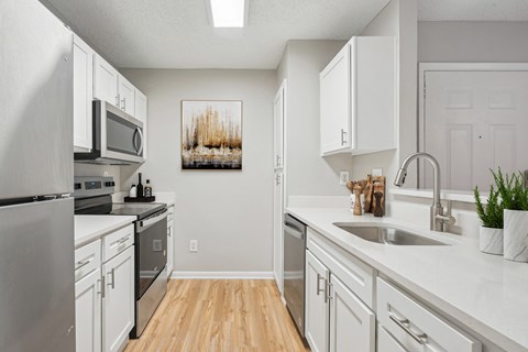 A kitchen with white cabinets and a wooden floor.