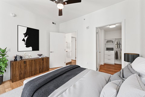 A bedroom with a bed in the foreground and a painting of a woman's profile on the wall.