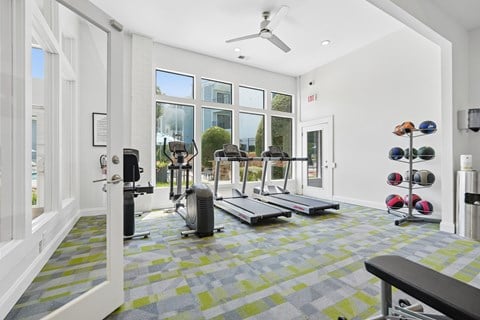 A gym with a variety of equipment including weights and treadmills.