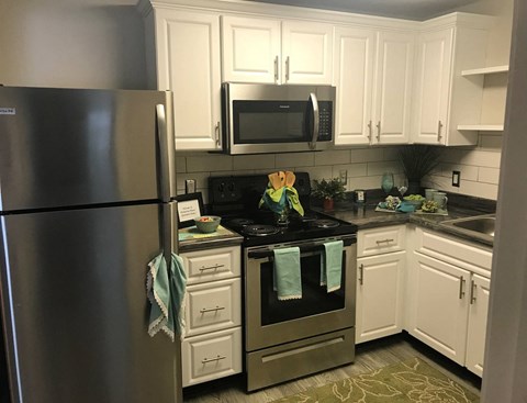 A kitchen with a stainless steel refrigerator and a black stove top.