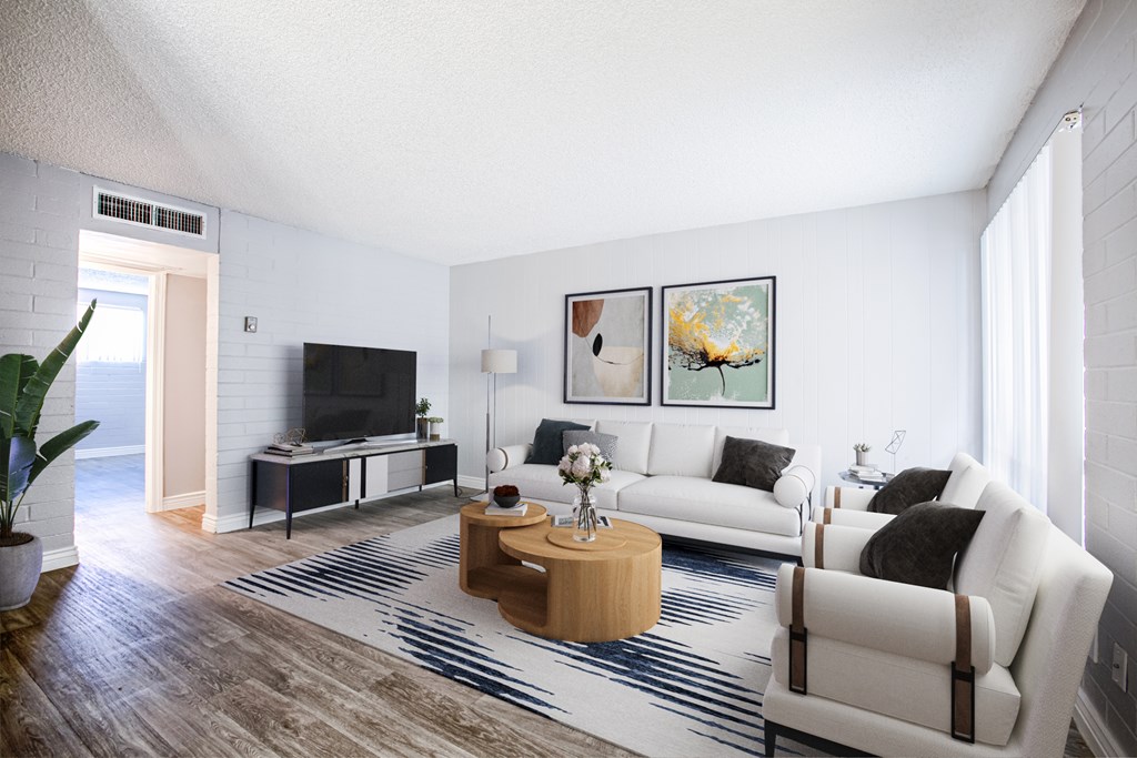 A living room with a white couch, a wooden coffee table, and a television.