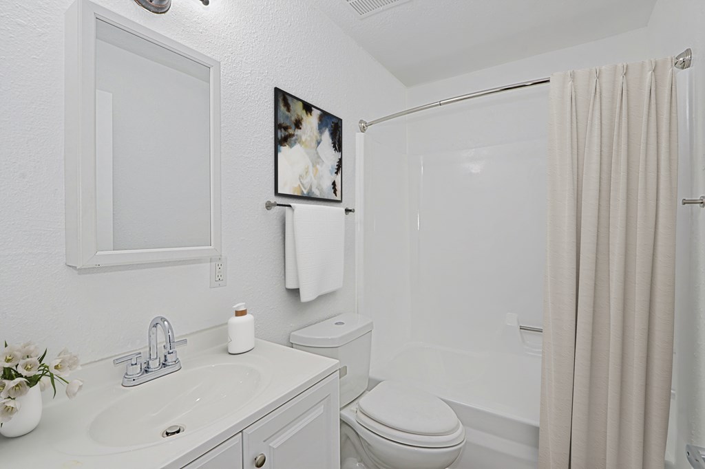A white bathroom with a toilet, sink, and shower.