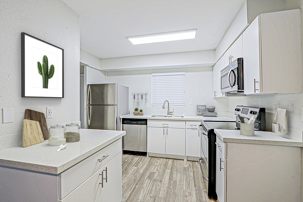 A kitchen with white cabinets and a fridge.