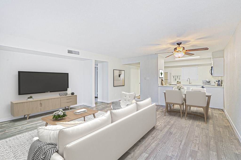 A living room with a television, couch, and chairs.