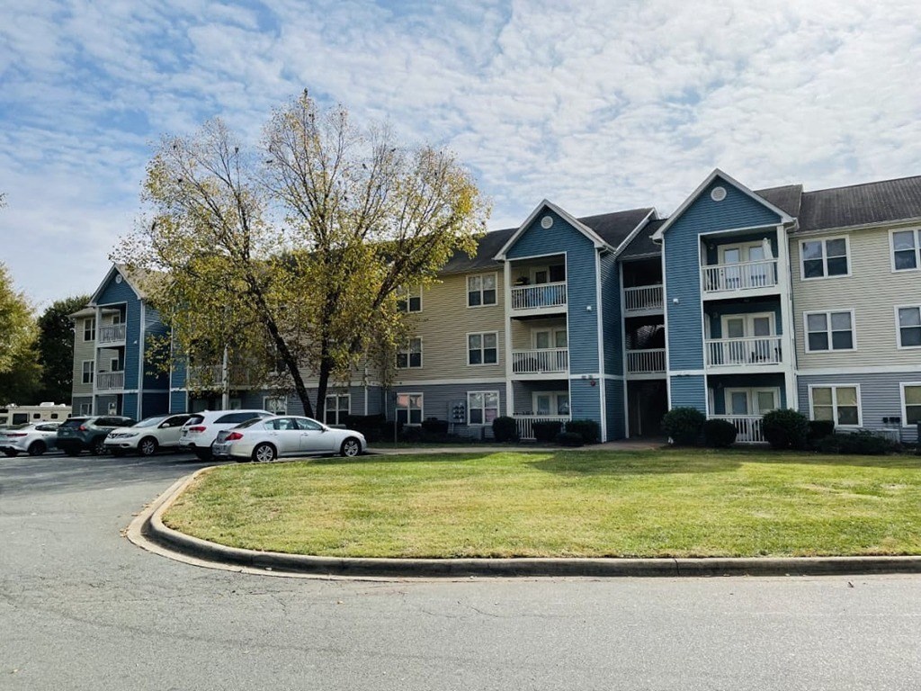 a row of apartment buildings with cars parked in front