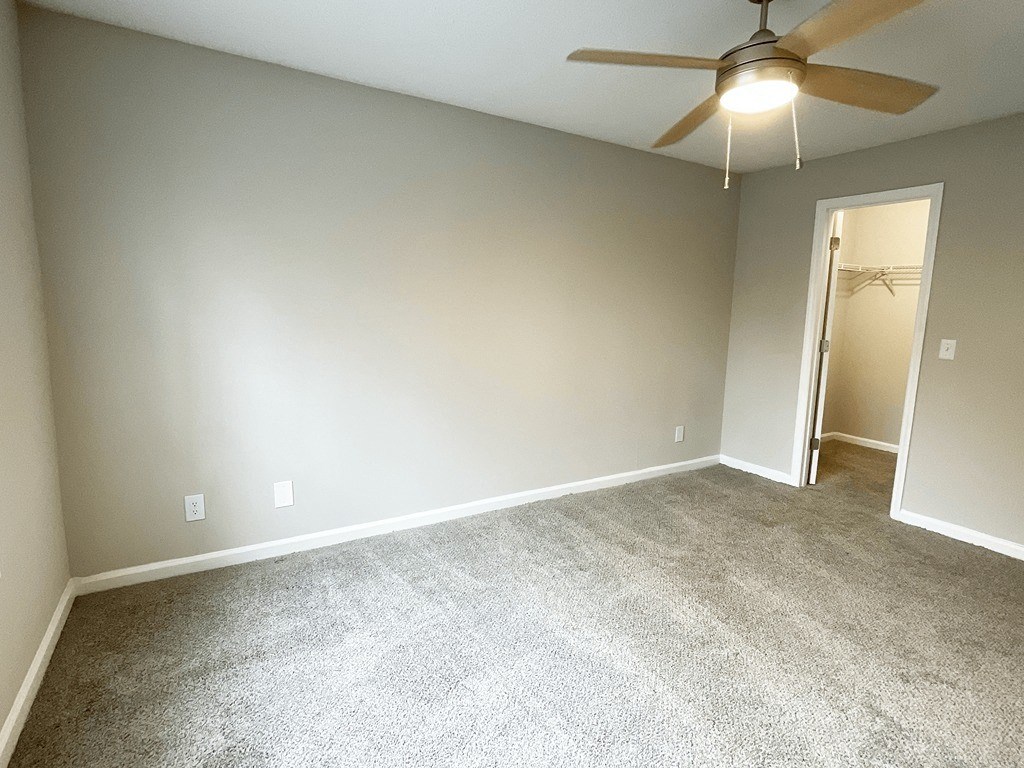 an empty living room with a ceiling fan