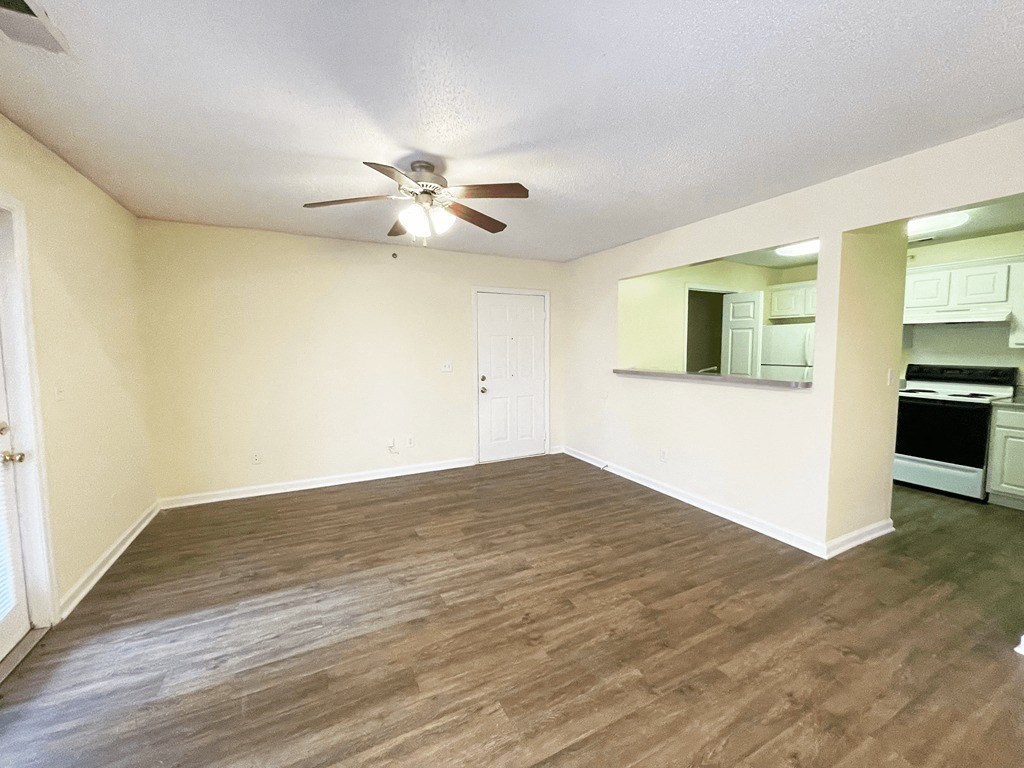 an empty living room and kitchen with a ceiling fan