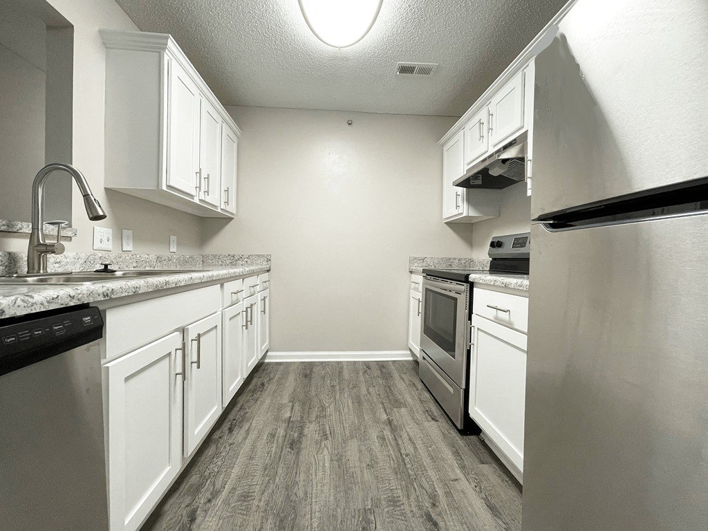 an empty kitchen with white cabinets and stainless steel appliances