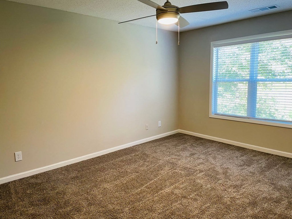 an empty room with a window and a ceiling fan